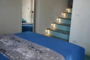 a bedroom with a blue bed and stairs with lights at Domus Julia in Furore