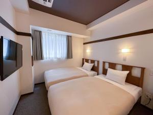 a hotel room with two beds and a flat screen tv at The OneFive Tokyo Shibuya in Tokyo