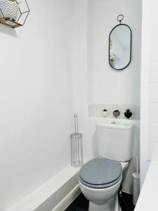a white bathroom with a toilet and a mirror at New fully furnished cosy home in Balderton