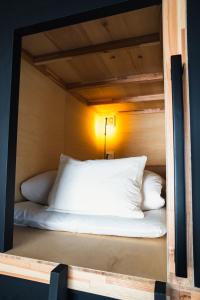 a bunk bed with white pillows in a room at EN PLUS Sauna and Capsule Bed 男性専用 in Kochi