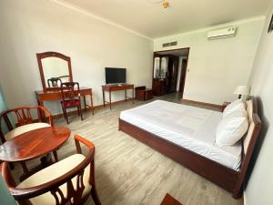 um quarto com uma cama, uma mesa e cadeiras em NGOC THU HOTEL em Soc Trang