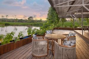 una terrazza con tavolo, sedie e un fiume di Bolagala Agro Floating Resort a Negombo
