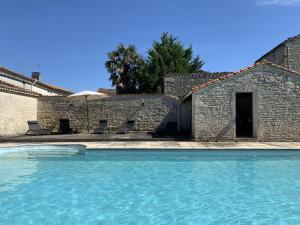 einem Pool vor einem Steingebäude in der Unterkunft The Cool Lounge à Coulonges - Charente in Coulonges