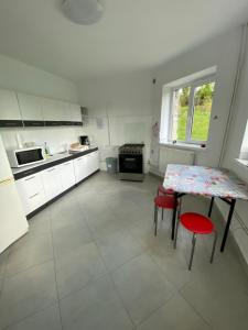 a white kitchen with a table and red chairs at Vila Onix in Sovata