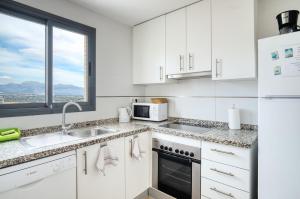 eine weiße Küche mit einer Spüle und einer Mikrowelle in der Unterkunft Platinum Lerida in Benidorm