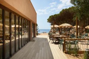 an outdoor patio with tables and umbrellas on the beach at Camping Cala Pola in Tossa de Mar