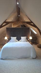 una camera da letto con un grande letto bianco in mansarda di La Limetière a Neuvy-le-Roi