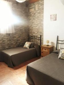 1 dormitorio con 2 camas y pared de ladrillo en Casa Rural El Almendrillo, en Arcos de la Frontera