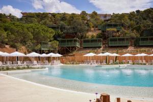 a swimming pool with chairs and umbrellas at Camping Cala Pola in Tossa de Mar