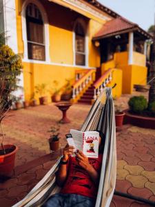 un hombre tendido en una hamaca leyendo un libro en Casa Do Leão A 150 year Old Portuguese Home en Nerul