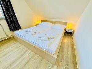 Schlafzimmer mit einem Bett mit weißer Bettwäsche und Kissen in der Unterkunft Ferienhaus Stoertebeker in Warnemünde