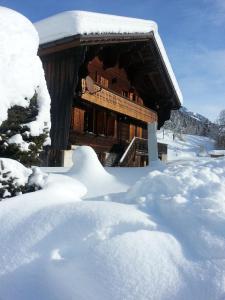 Cabaña de madera cubierta de nieve con una pila de nieve en B&B Chalet la Croisée, en Vers L'Eglise