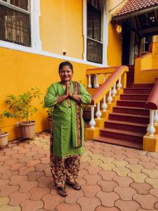 une femme debout devant un bâtiment jaune dans l'établissement Casa Do Leão A 150 year Old Portuguese Home, à Nerul