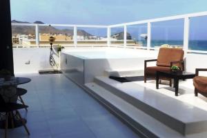 einen Balkon mit einem Stuhl, einem Tisch und Meerblick in der Unterkunft New Luxury PH w/ Pool. Ocean, Mountain & City View in Mindelo