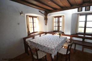 comedor con mesa, sillas y ventanas en Dormouse House in Slovenia en Grahovo