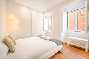 a white bedroom with a bed and a window at GuestReady - Lemon House with Private Garden in Lisbon