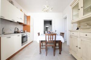 een witte keuken met een tafel en stoelen. bij Casa Beatrice in Caprarica di Lecce