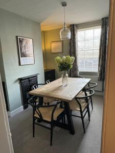 a dining room table with chairs and a vase of flowers at Chester City Centre townhouse in Chester