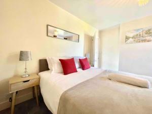 um quarto com 2 camas e almofadas vermelhas em The Lancaster - relax and enjoy home near City Center with parking em Canterbury