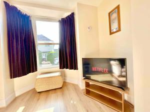 a living room with a flat screen tv next to a window at The Lancaster - relax and enjoy home near City Center with parking in Canterbury