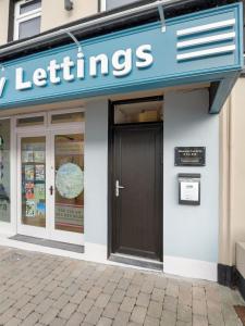 a store front with a black door and a sign at Town centre apartment, Clifden in Clifden