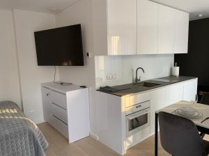 a kitchen with white cabinets and a sink and a table at Ievos apartamentai in Pervalka