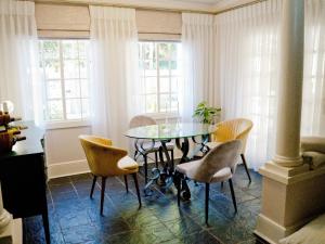 uma sala de jantar com uma mesa de vidro e cadeiras em The Sweet Rose em Bloemfontein