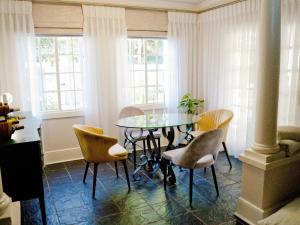 Un comedor con una mesa de cristal y sillas. en The Sweet Rose, en Bloemfontein