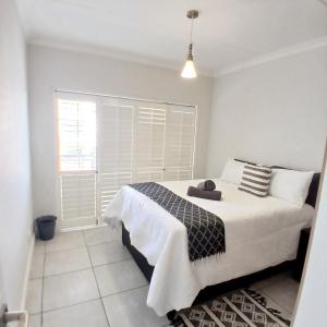 een slaapkamer met een bed en een raam met witte luiken bij The Luxe Marvelous Apartment in Pretoria