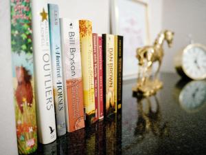 eine Reihe von Büchern auf einem Tisch mit einer Uhr in der Unterkunft The Sweet Rose in Bloemfontein