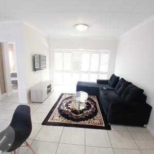 een woonkamer met een zwarte bank en een tafel bij The Luxe Marvelous Apartment in Pretoria