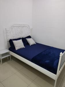 un letto bianco con lenzuola e cuscini blu; di ART CASIA HOMESTAY BERTAM a Kepala Batas