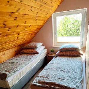 two beds in a attic room with a window at Domki Zagroda in Jastrzębia Góra