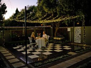 um homem e uma mulher sentados numa mesa num jardim com luzes em The Sweet Rose em Bloemfontein