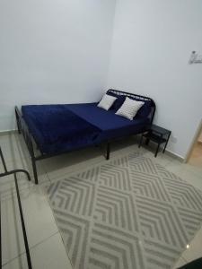 una camera da letto con un letto con lenzuola blu e un tappeto di ART CASIA HOMESTAY BERTAM a Kepala Batas