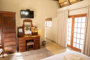 a bedroom with a dresser and a desk with a mirror at La La Nathi Country Guesthouse in Harrismith