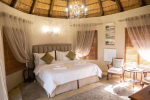 a bedroom with a white bed and a chandelier at La La Nathi Country Guesthouse in Harrismith