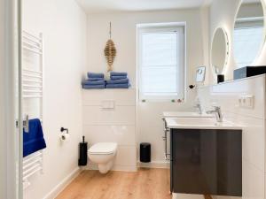 a white bathroom with a toilet and a sink at Beach Loft in Zingst