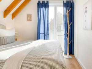 a bedroom with a bed with blue curtains and a window at Beach Loft in Zingst