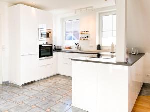 una cocina blanca con armarios y electrodomésticos blancos en Bi de Wisch, OG, en Prerow