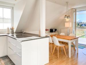 a kitchen and dining room with white cabinets and a wooden table at Bi de Wisch, OG in Prerow