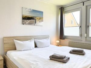 a bedroom with a bed with white sheets and a window at Boddenwind No 2 in Zingst