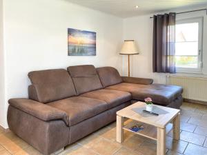 a living room with a brown couch and a table at Boddenwind No 3 in Zingst