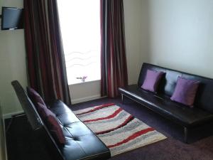 a living room with a leather couch and a window at Cambridge Hotel Waterfront in Brighouse