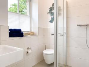La salle de bains blanche est pourvue de toilettes et d'un lavabo. dans l'établissement Cozy One, à Zingst