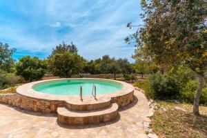 a swimming pool with a stone wall around it at Villa con piscina 429 in Torre Pali 