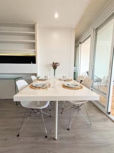 a white dining room table with white chairs and a large window at Spacious Studio by the University in San Vicente del Raspeig