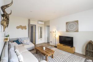a living room with a white couch and a tv at Résidence CasaBianca Porticcio - Nino in Grosseto-Prugna