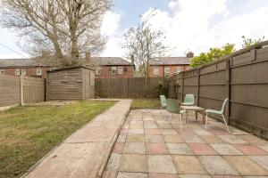 een patio met 2 stoelen, een tafel en een hek bij Spacious 4 bedroom home - sleeps 8 in Manchester