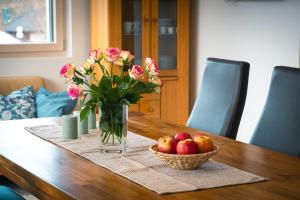 a vase of flowers and a basket of apples on a table at Ferienwohnung Weitblick in Bruchweiler-Bärenbach